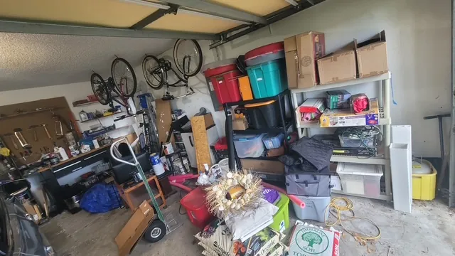 Garage cleanout before in Dunedin, FL — cluttered bay with bikes and bins
